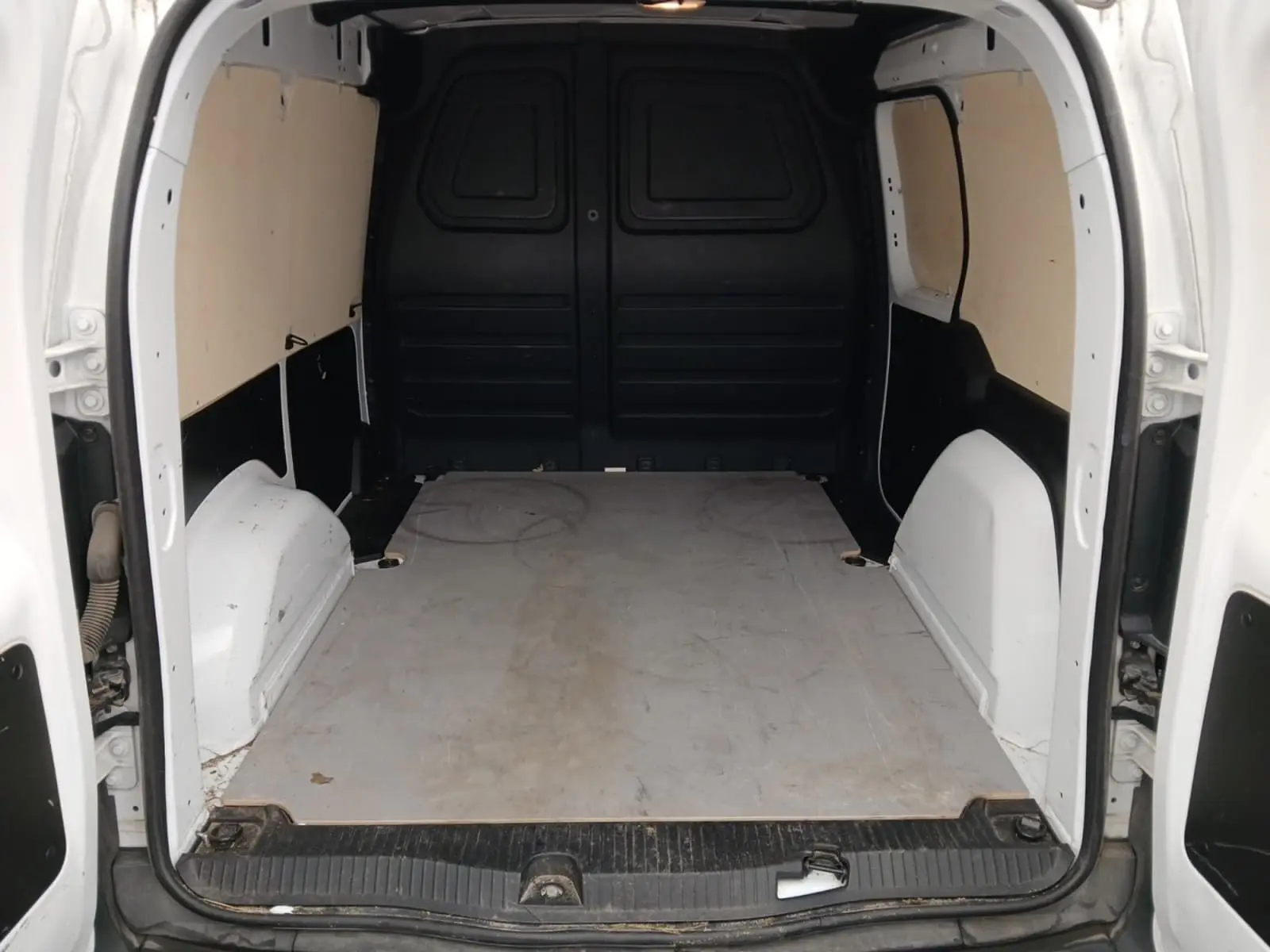 Intérieur du coffre arrière blanc du Renault Kangoo Van 2024, vue de l'ouverture avec plancher plat et parois protégées.