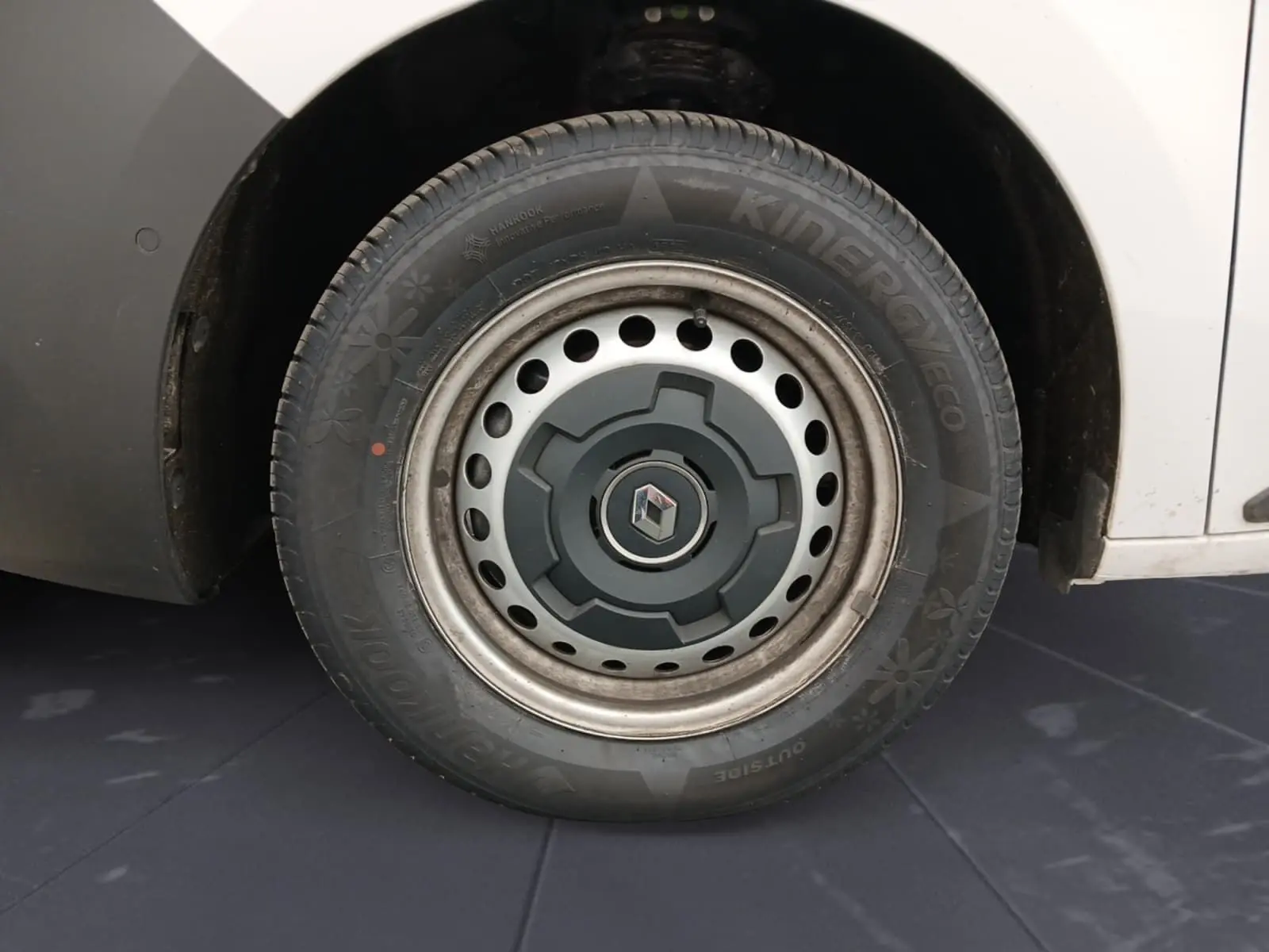 Gros plan sur la roue avant droite du Renault Kangoo blanc 2024 avec jante acier et logo Renault central.