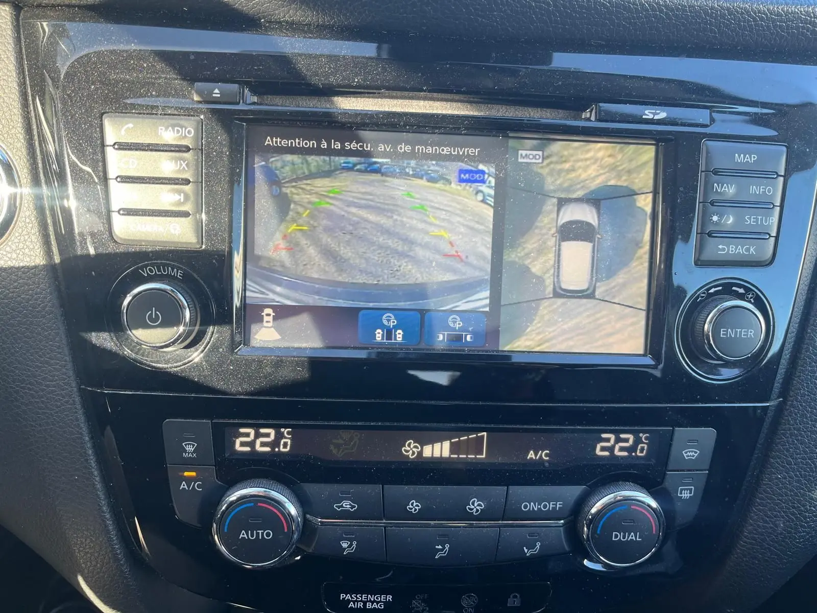 Vue rapprochée de l’écran tactile du Nissan Qashqai noir montrant la caméra de recul et les commandes de climatisation à 22°C.