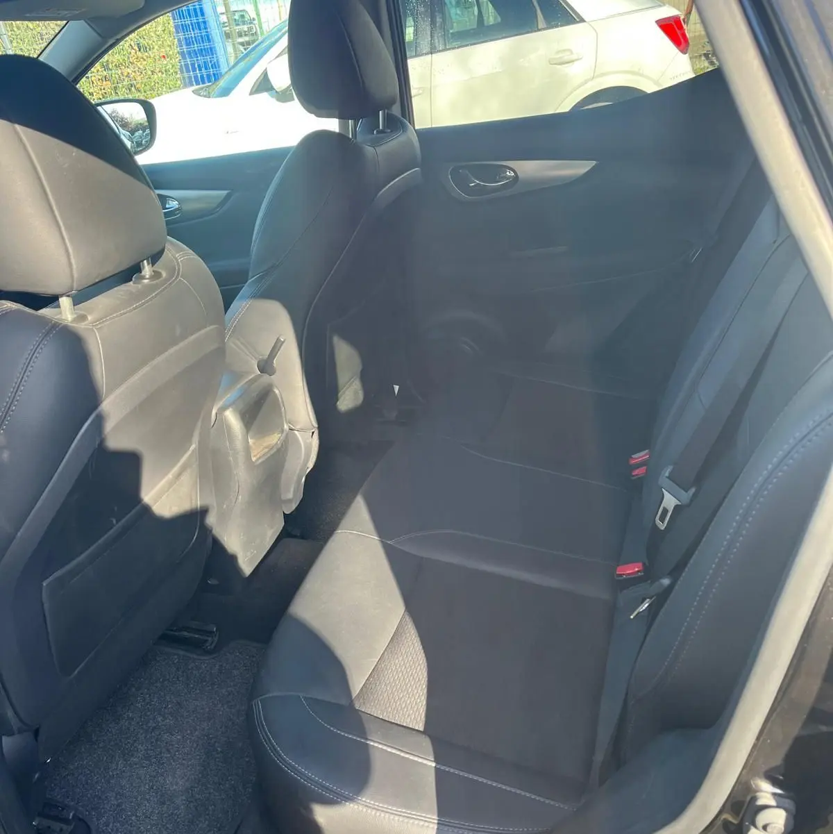 Vue intérieure côté droit des sièges arrière en cuir noir du Nissan Qashqai II PH2 2017 avec ceintures visibles.