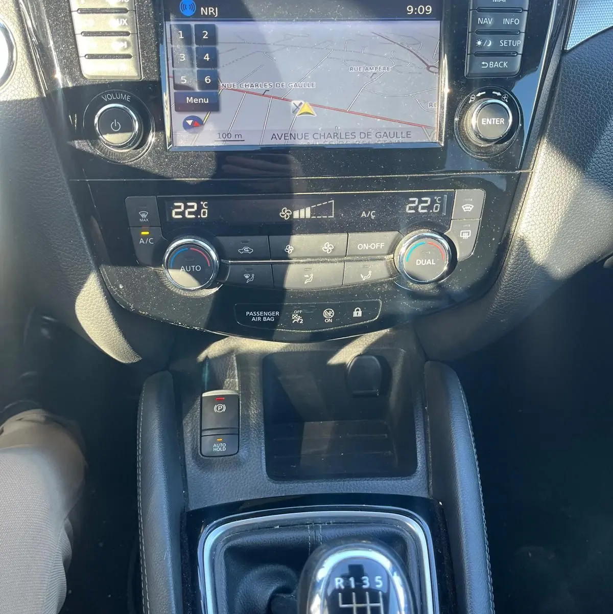 Vue rapprochée de la console centrale du Nissan Qashqai noir, avec écran tactile GPS et levier de vitesse manuel.