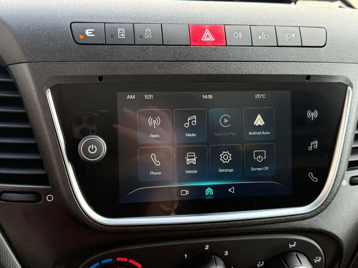 Écran tactile central du tableau de bord du Iveco Daily blanc 2026 avec commandes multimédia et boutons de sécurité.