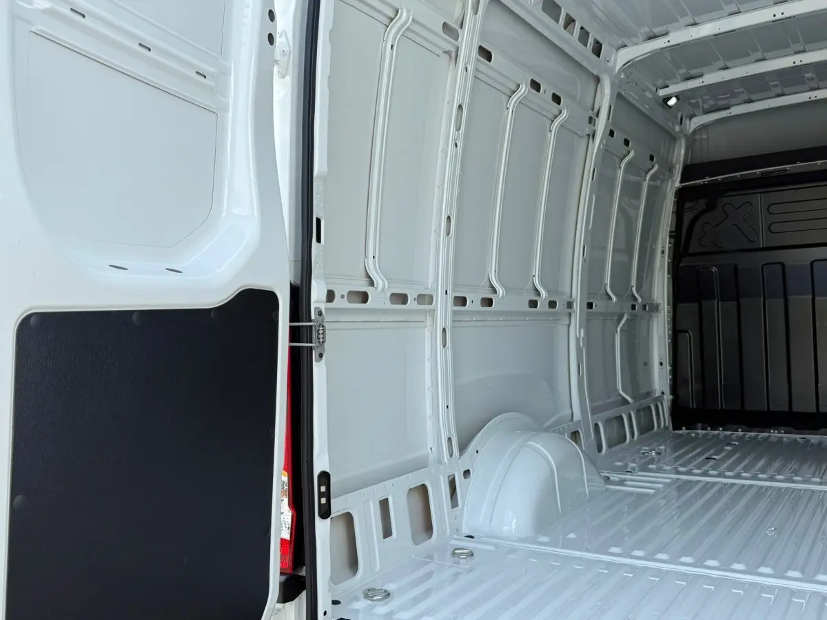 Vue intérieure arrière du fourgon Iveco Daily blanc 2026, montrant l'espace de chargement vide et les parois métalliques.
