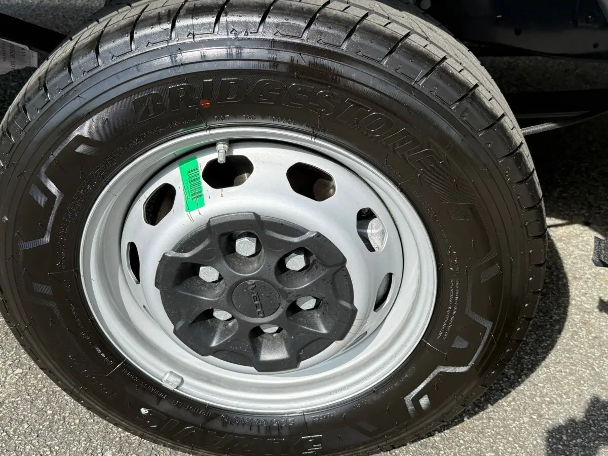 Gros plan sur la roue avant droite du Iveco Daily 2.3 35S16 V12 blanc avec jante acier et pneu Bridgestone.