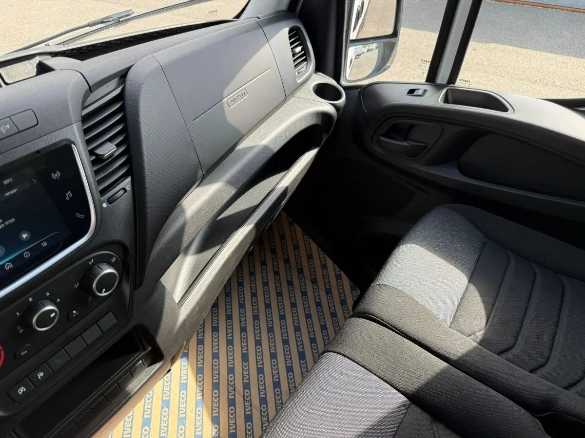 Vue intérieure côté passager de l'IVECO Daily blanc 2026, montrant tableau de bord et siège tissu gris.