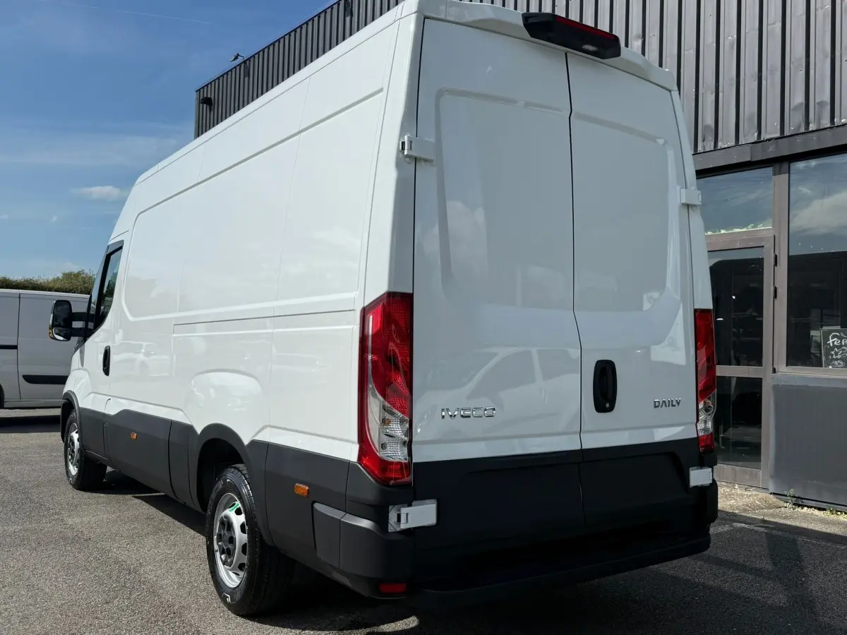 IVECO Daily blanc vu en 3/4 arrière droit, avec portes arrière fermées et feux rouges verticaux visibles.