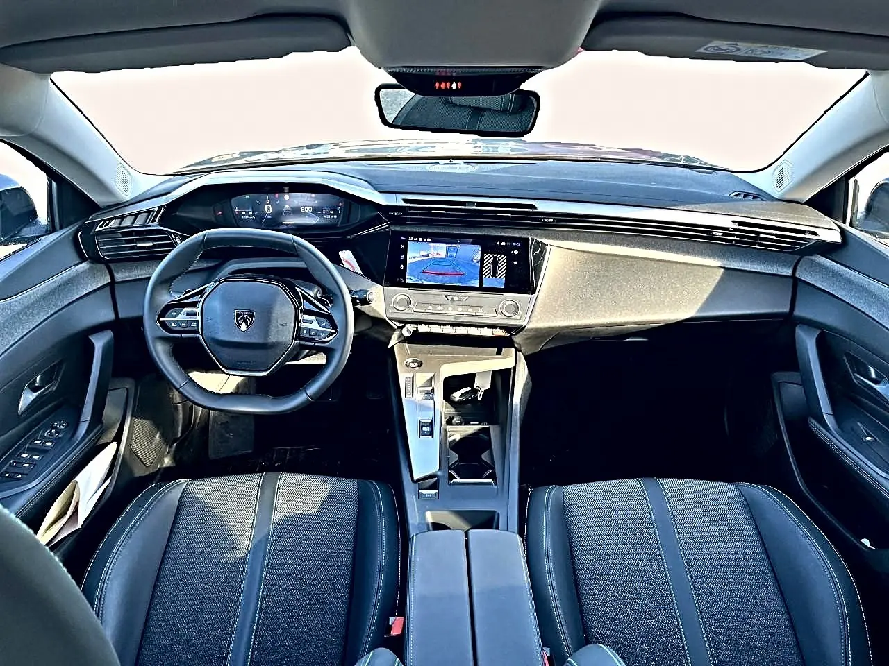 Vue intérieure avant de la Peugeot 308 2025, tableau de bord moderne avec écran tactile et volant multifonction noir.