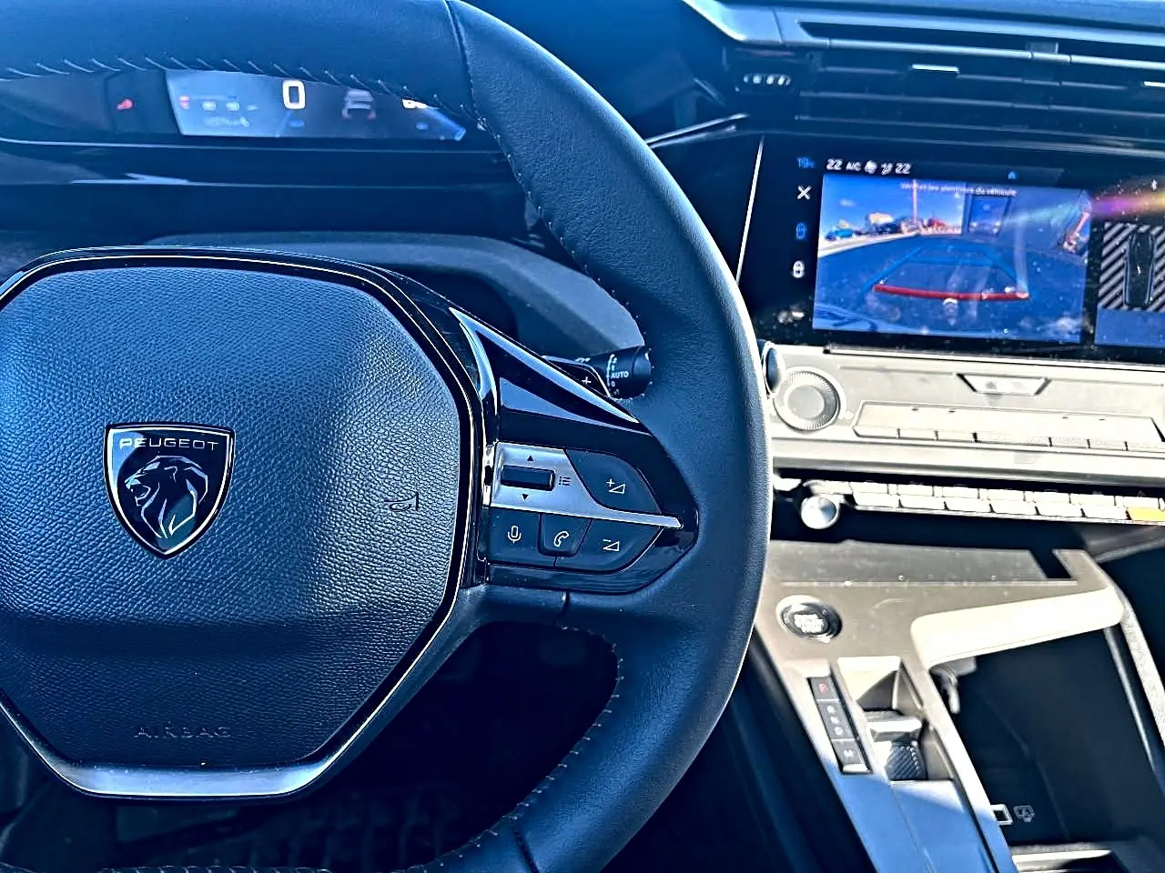 Vue intérieure centrée sur le volant multifonction Peugeot 308 gris selenium avec écran tactile affichant la caméra de recul.