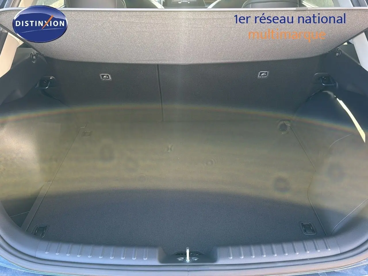 Coffre ouvert du Kia Niro 2025 bleu minéral métal, vue plongeante montrant l'espace de chargement vide et propre.