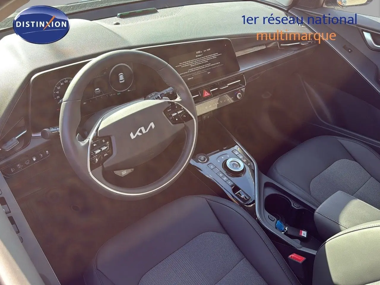 Vue intérieure du poste de conduite du Kia Niro 2025, volant multifonction et console centrale moderne en cuir noir.