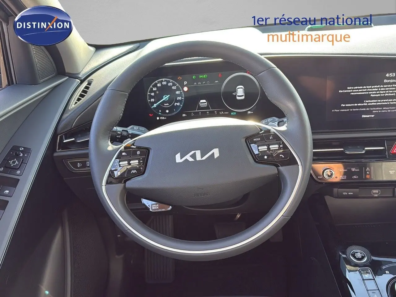 Vue intérieure centrée sur le volant KIA d'un Niro hybride rechargeable 2025 avec tableau de bord numérique et commandes intégrées.