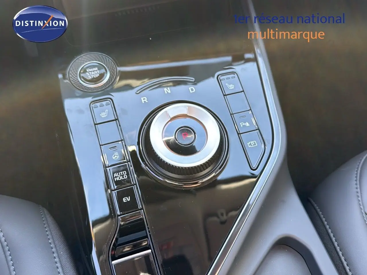 Gros plan sur la console centrale noire brillante du Kia Niro 2025, avec molette de sélection de vitesse et boutons fonctionnels.