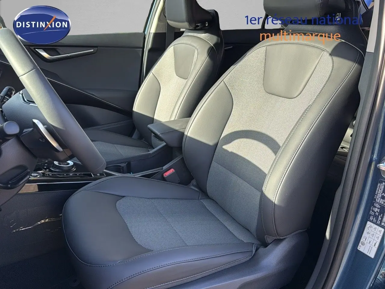 Vue intérieure rapprochée des sièges avant en cuir noir du Kia Niro 2025 bleu minéral métal, côté conducteur ouvert.