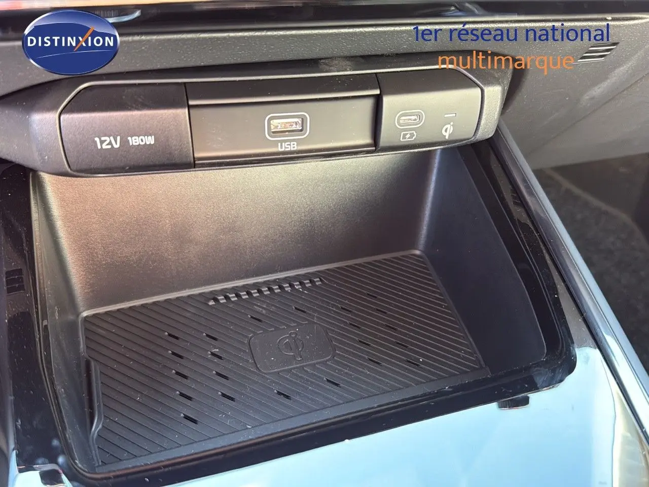 Gros plan sur la console centrale du Kia Niro 2025, avec prise USB, port 12V et chargeur sans fil Qi.