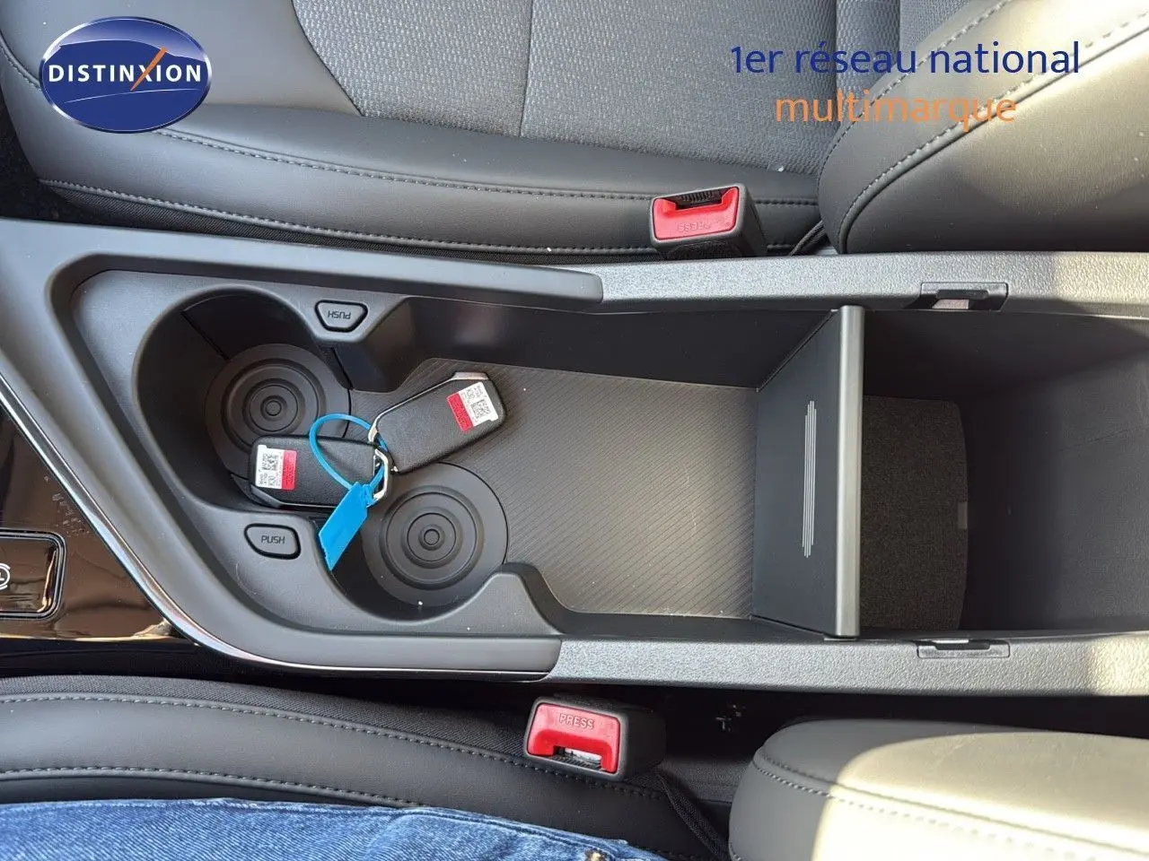 Gros plan sur la console centrale avec porte-gobelets et clés, intérieur cuir noir du Kia Niro 2025.