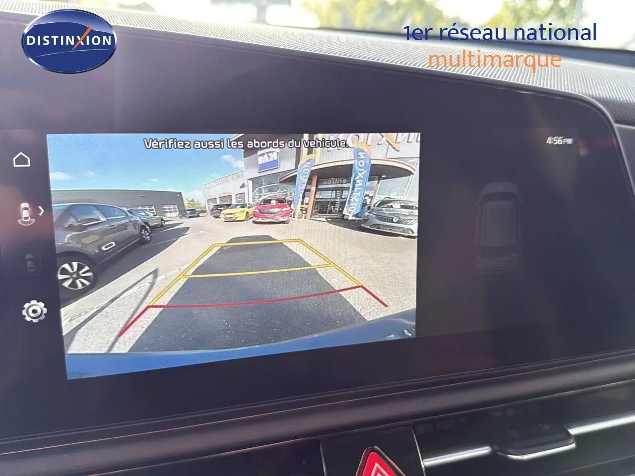 Écran tactile affichant la caméra de recul du Kia Niro bleu minéral, avec lignes de guidage et vue arrière du parking.