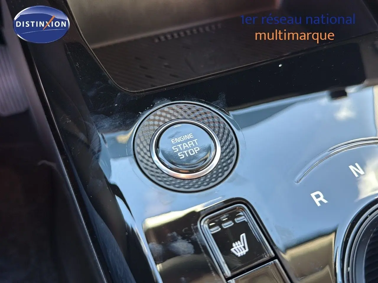 Gros plan sur la console centrale noire brillante du Kia Niro 2025, avec bouton start/stop et commande siège chauffant.