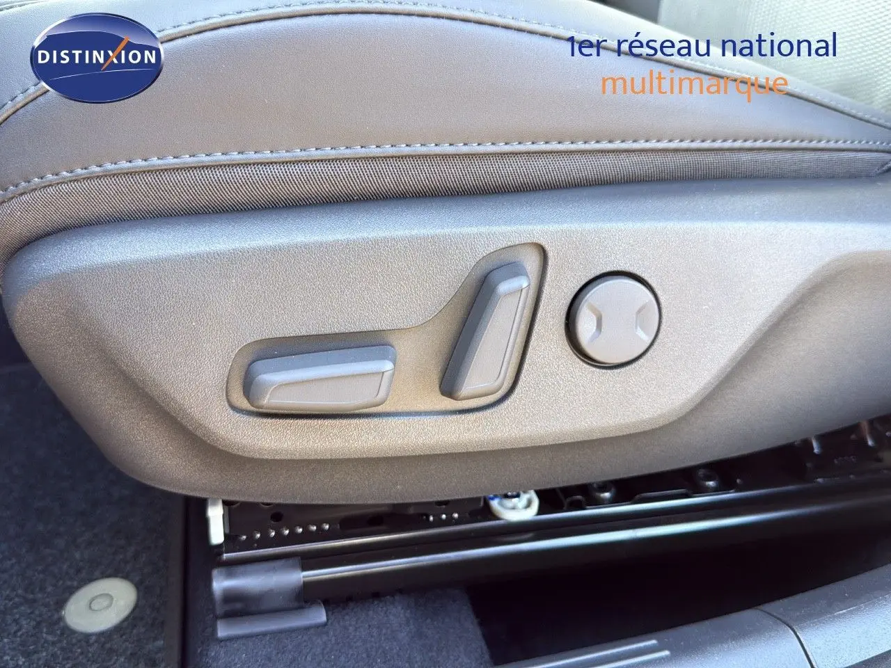 Gros plan sur les commandes électriques du siège conducteur en cuir gris du Kia Niro bleu minéral 2025.