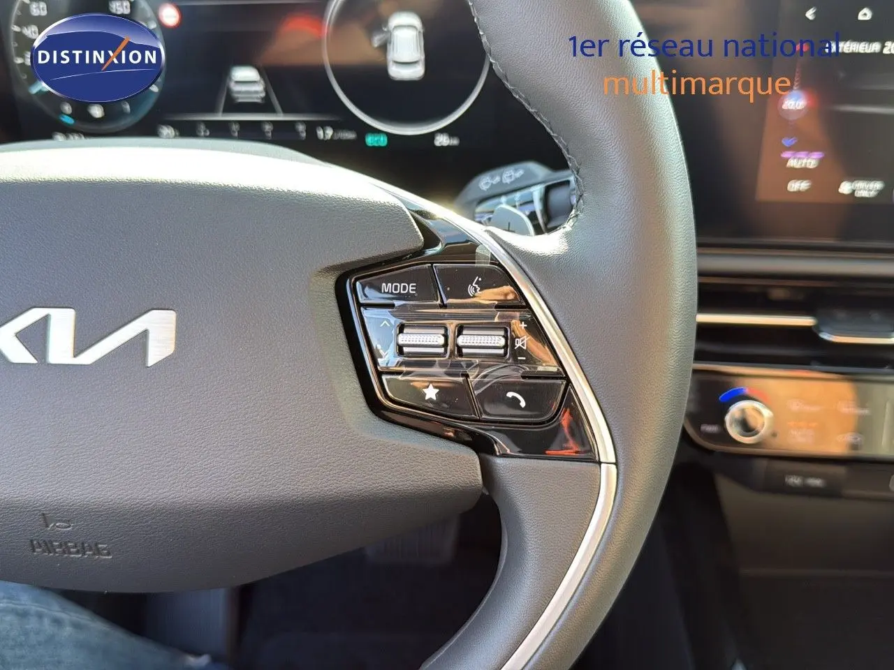 Gros plan sur le côté droit du volant en cuir noir du Kia Niro 2025, avec commandes intégrées et tableau de bord numérique flou.