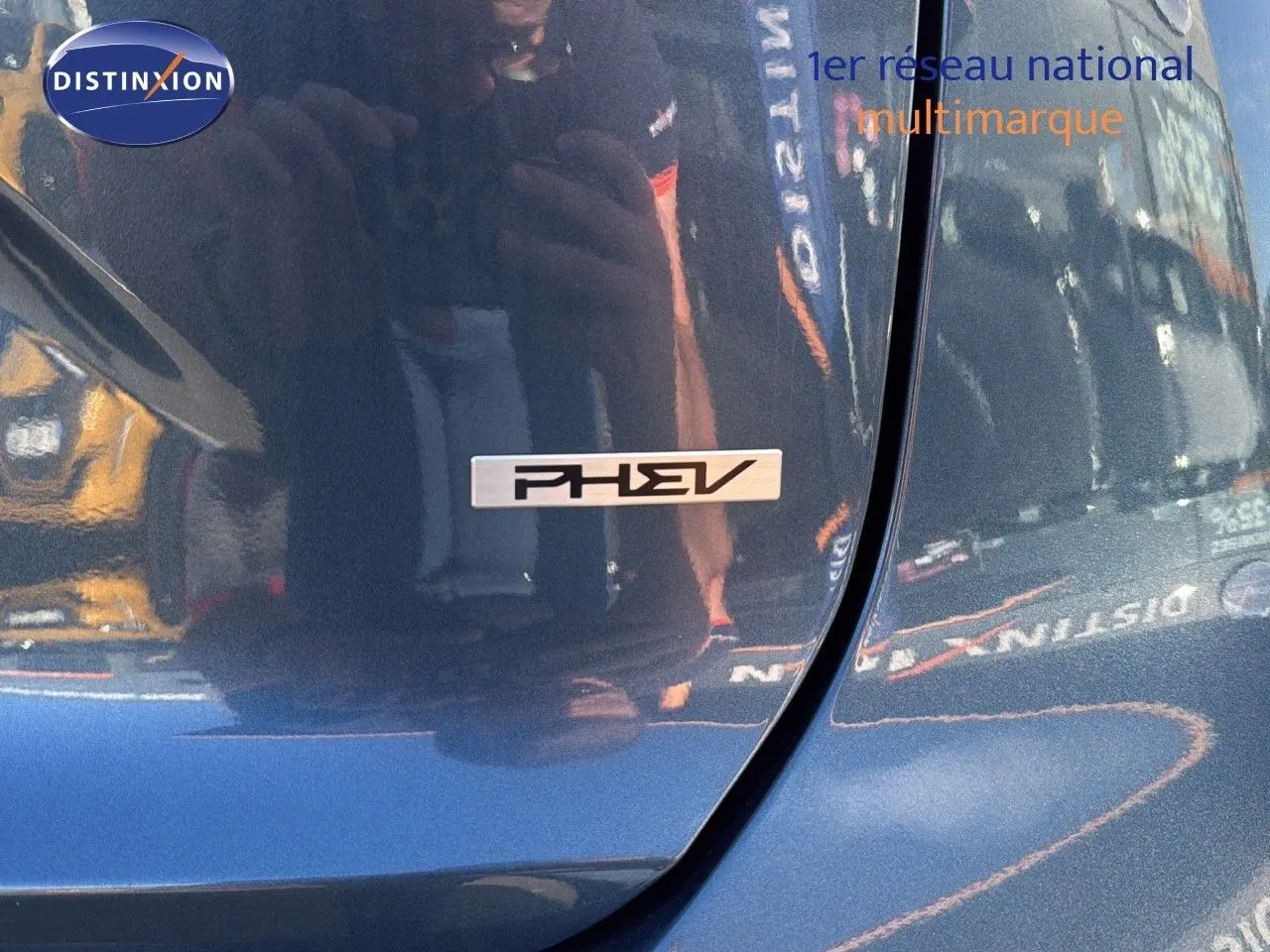 Gros plan sur l'emblème PHEV sur la porte arrière droite d'un Kia Niro bleu minéral métal 2025 hybride rechargeable.