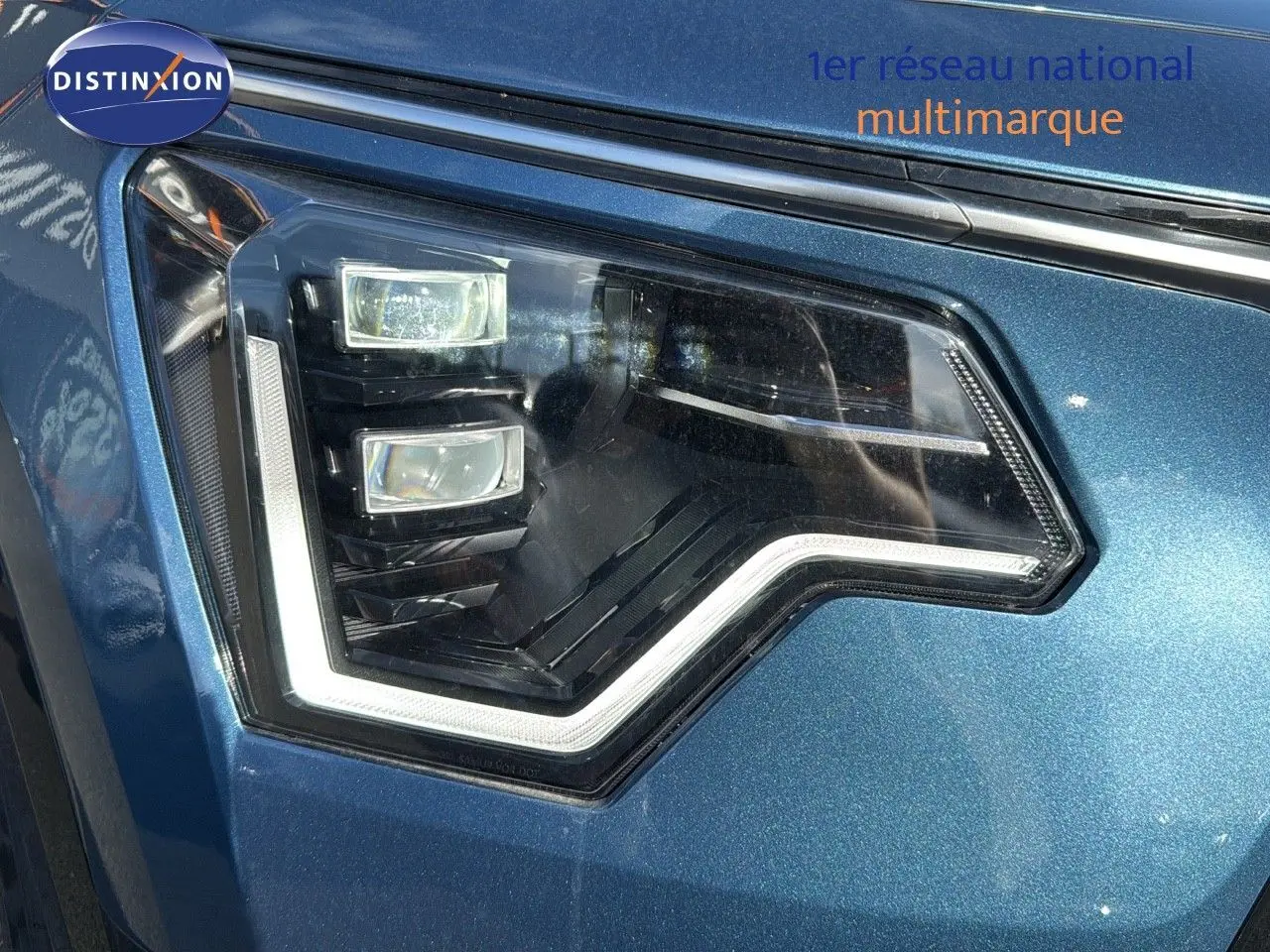 Gros plan sur le phare avant gauche du KIA NIRO 2025 en bleu minéral métal avec éclairage LED distinctif.