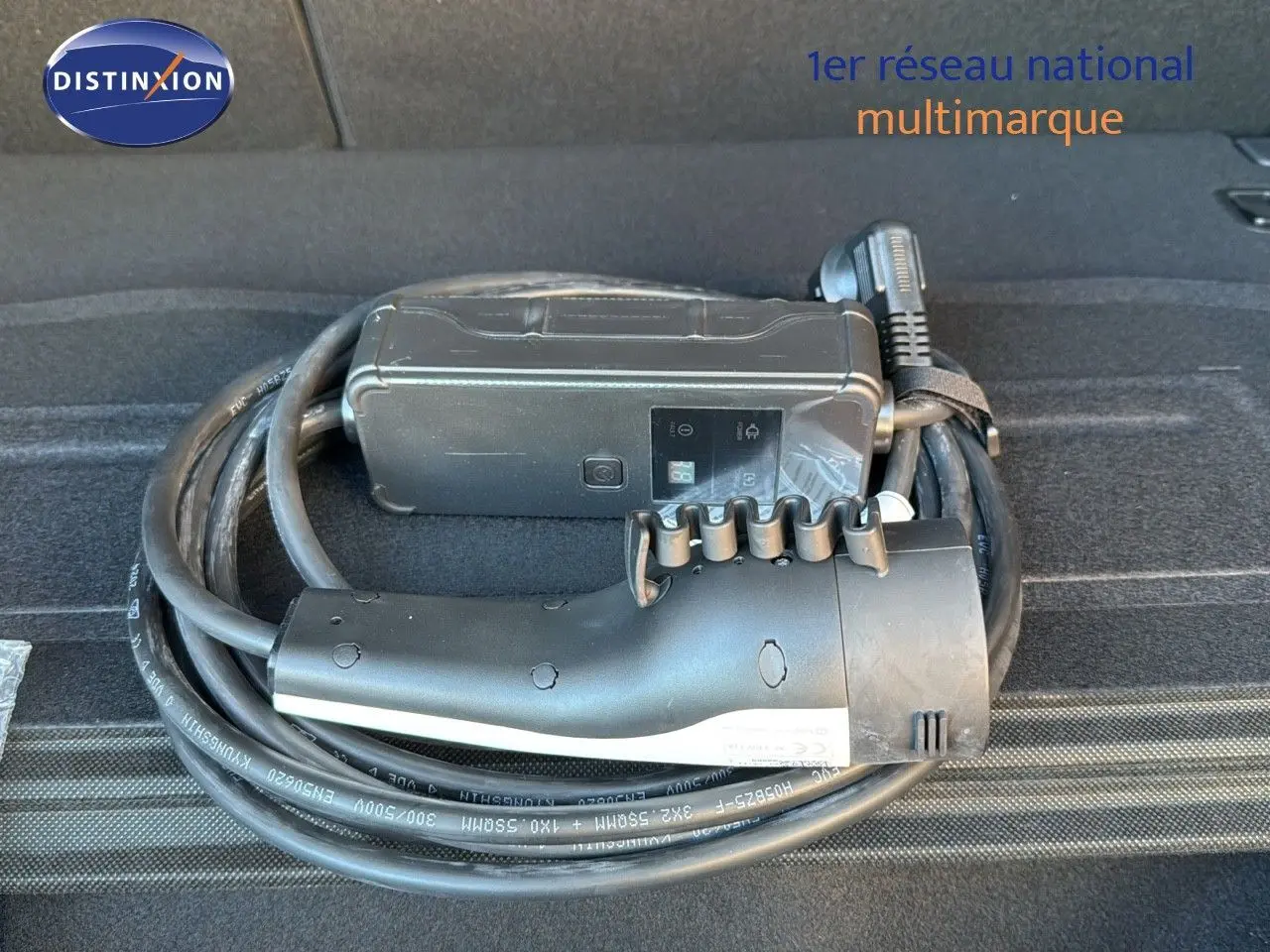 Câble de recharge noir enroulé dans le coffre d'une Kia Niro hybride rechargeable bleu minéral.