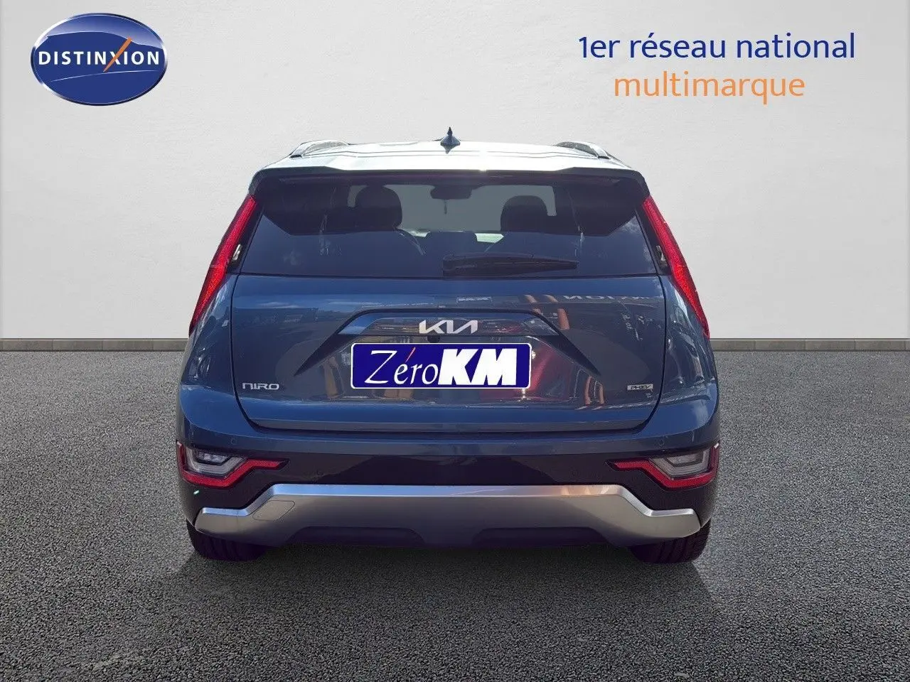 Vue arrière d'un Kia Niro bleu minéral metal 2025 avec feux arrière verticaux et logo distinctif sur le hayon.