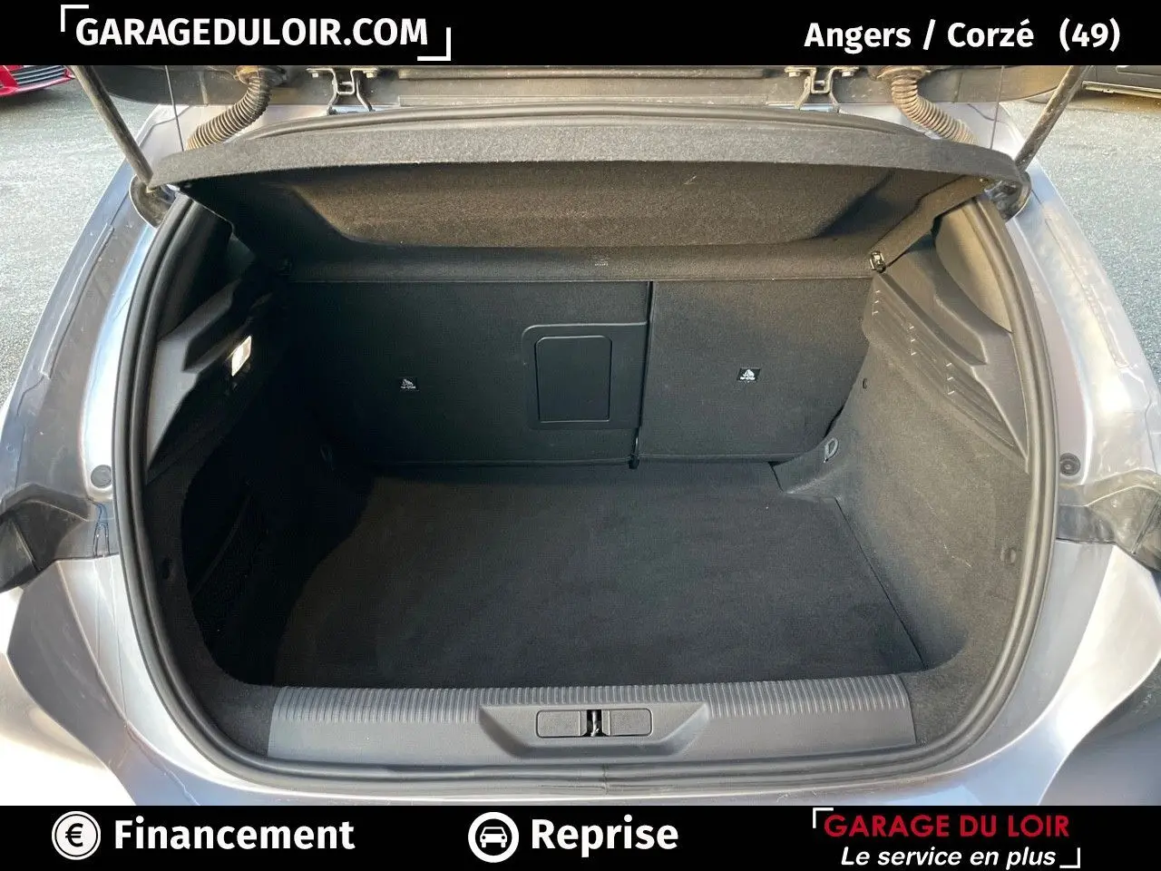 Coffre ouvert d'une Peugeot 308 gris Artense vue de l'arrière, montrant un espace de chargement propre et spacieux.