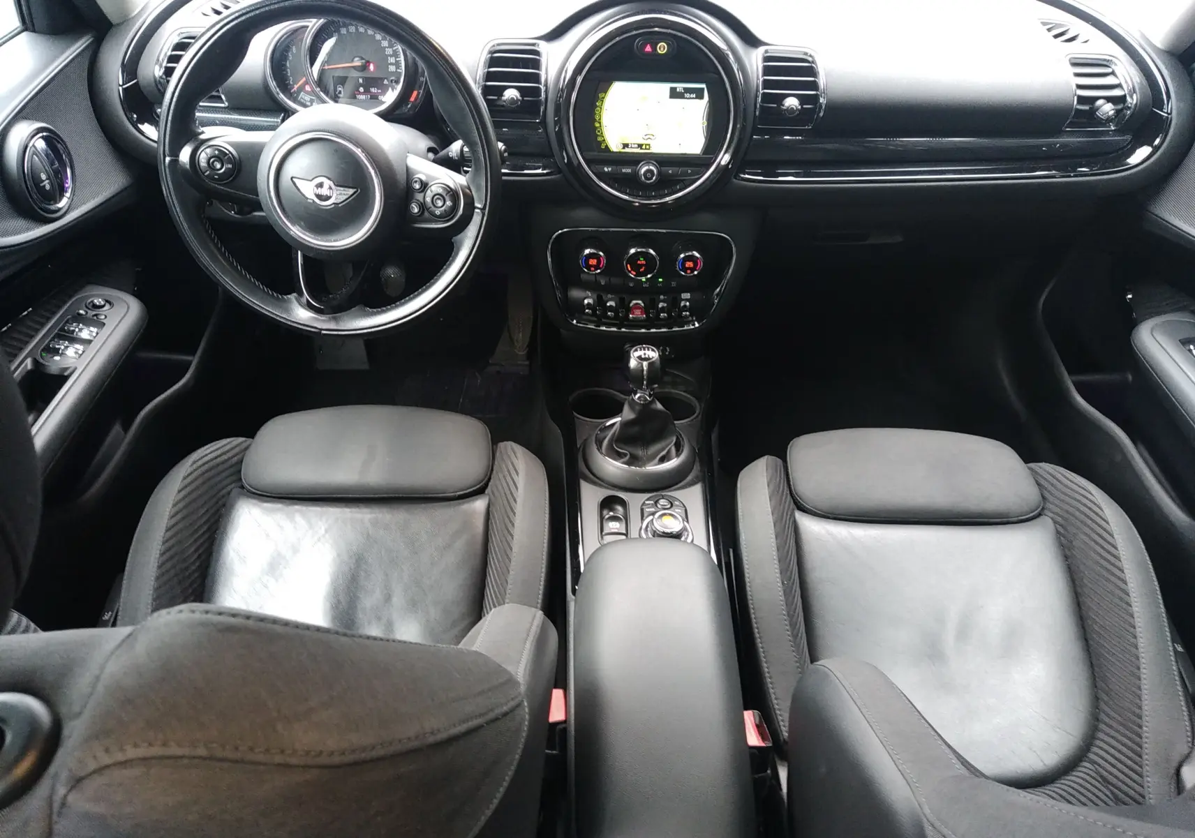 Vue intérieure avant de la MINI CLUBMAN F54 2017, mettant en valeur le tableau de bord noir et la boîte manuelle.