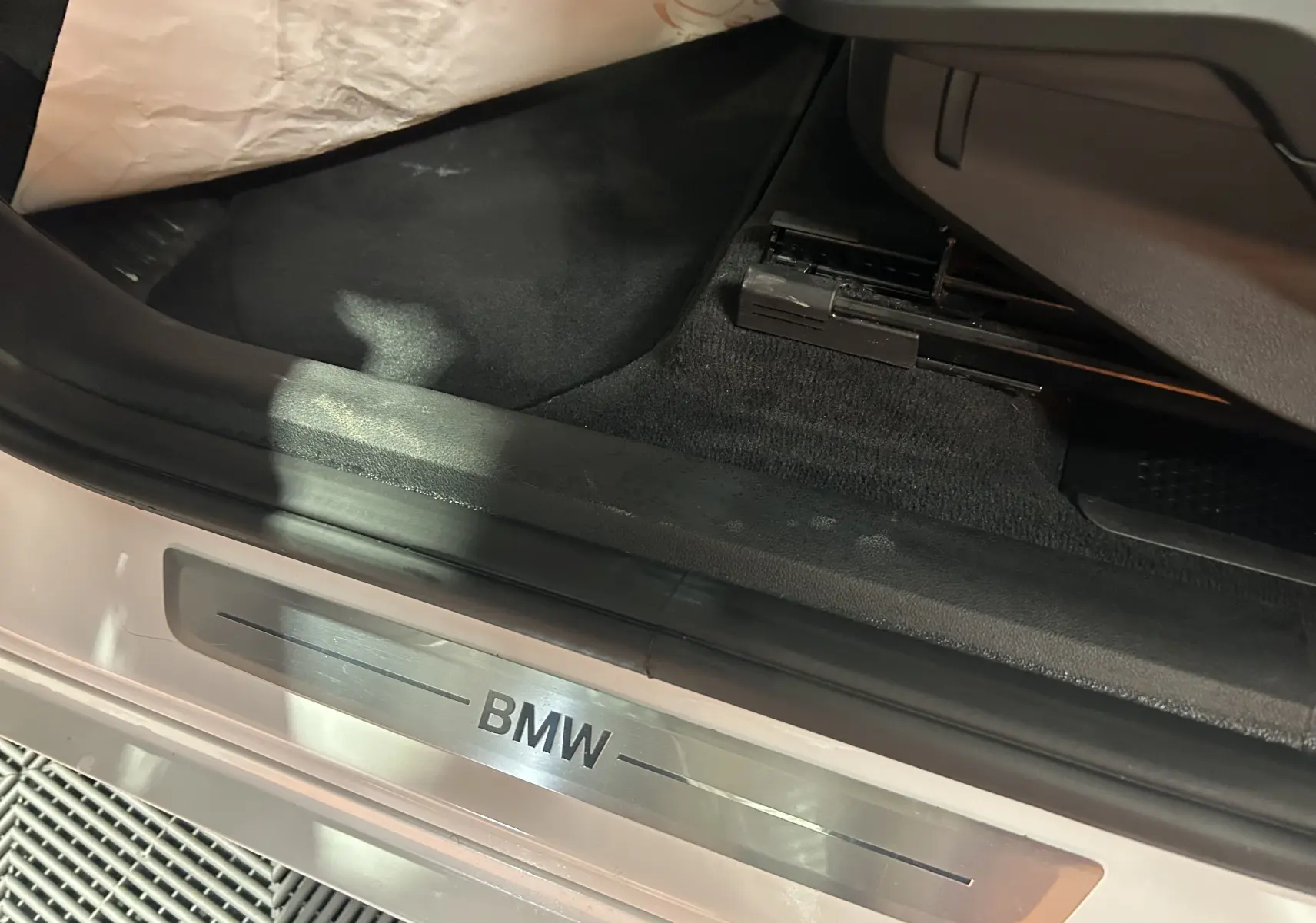 Gros plan sur le seuil de porte côté conducteur d'une BMW Série 2 Active Tourer blanche avec logo BMW en métal brossé.