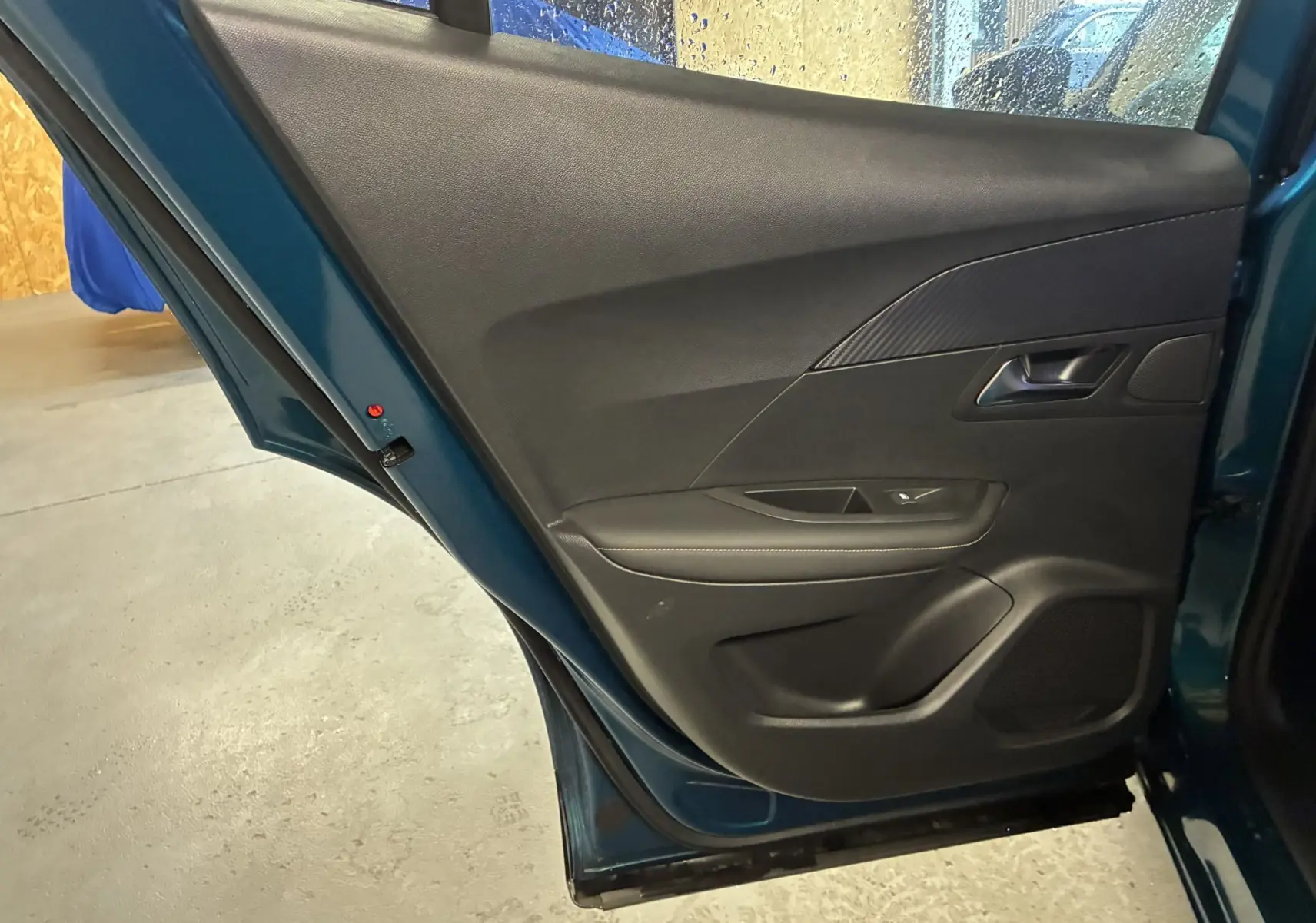 Vue intérieure de la porte arrière gauche bleu métallisé du Peugeot 2008 1.2 Hybrid 136 Allure avec garniture noire.