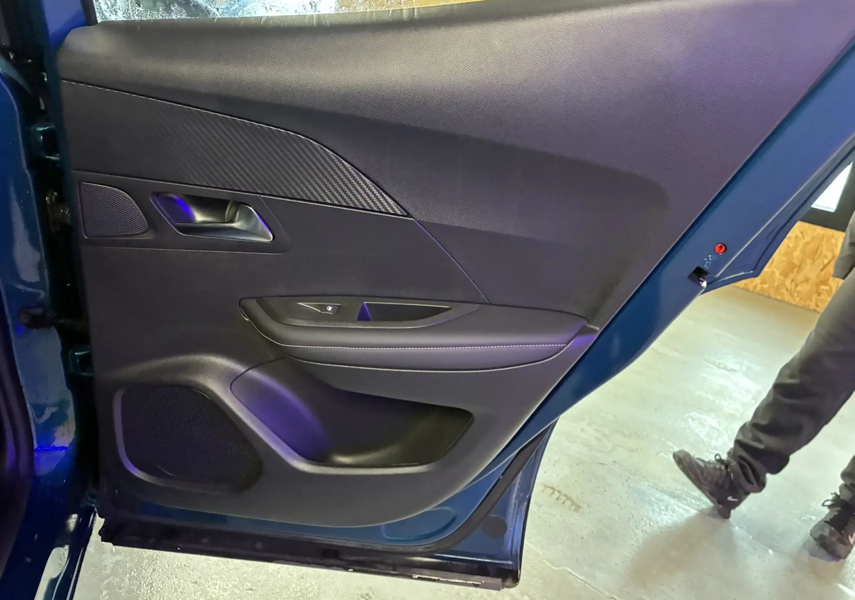 Vue intérieure de la porte arrière gauche bleu du Peugeot 2008 1.2 Hybrid 136 Allure avec garniture noire et poignée intégrée.