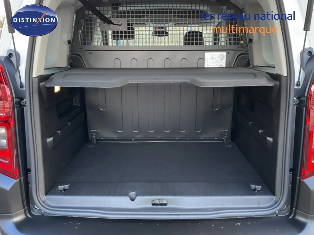 Coffre ouvert d’un Citroën Berlingo blanc glacier 2025, vue arrière montrant l’espace de chargement et la grille de séparation.