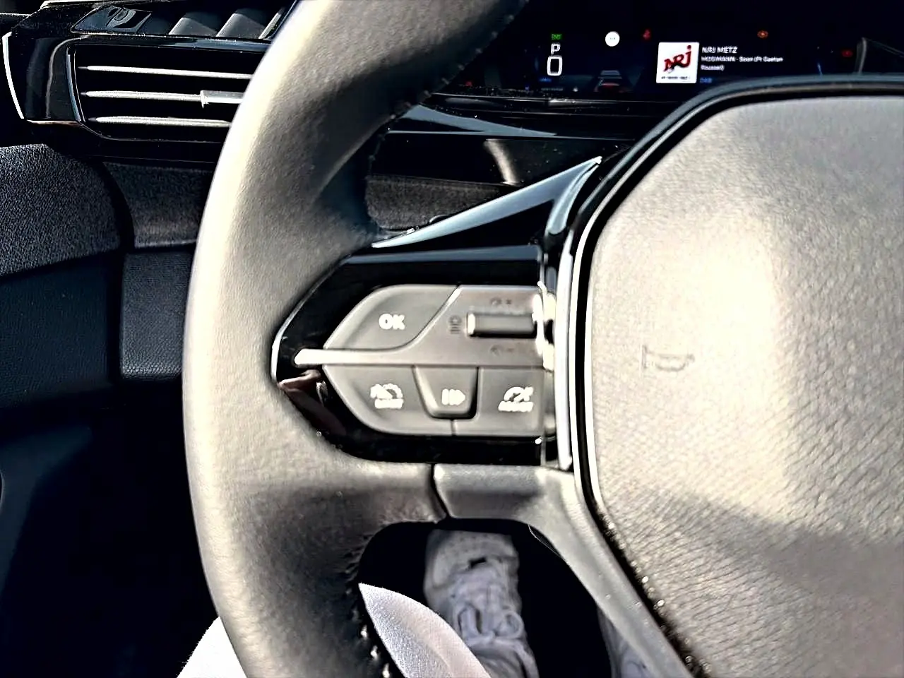 Gros plan sur le volant noir multifonction de la Peugeot 308 2025 avec commandes intégrées côté gauche.