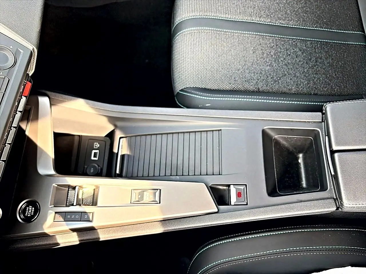 Vue plongeante sur la console centrale noire de la Peugeot 308 1.5 BlueHDi 130 Allure avec boîte auto et accoudoir.