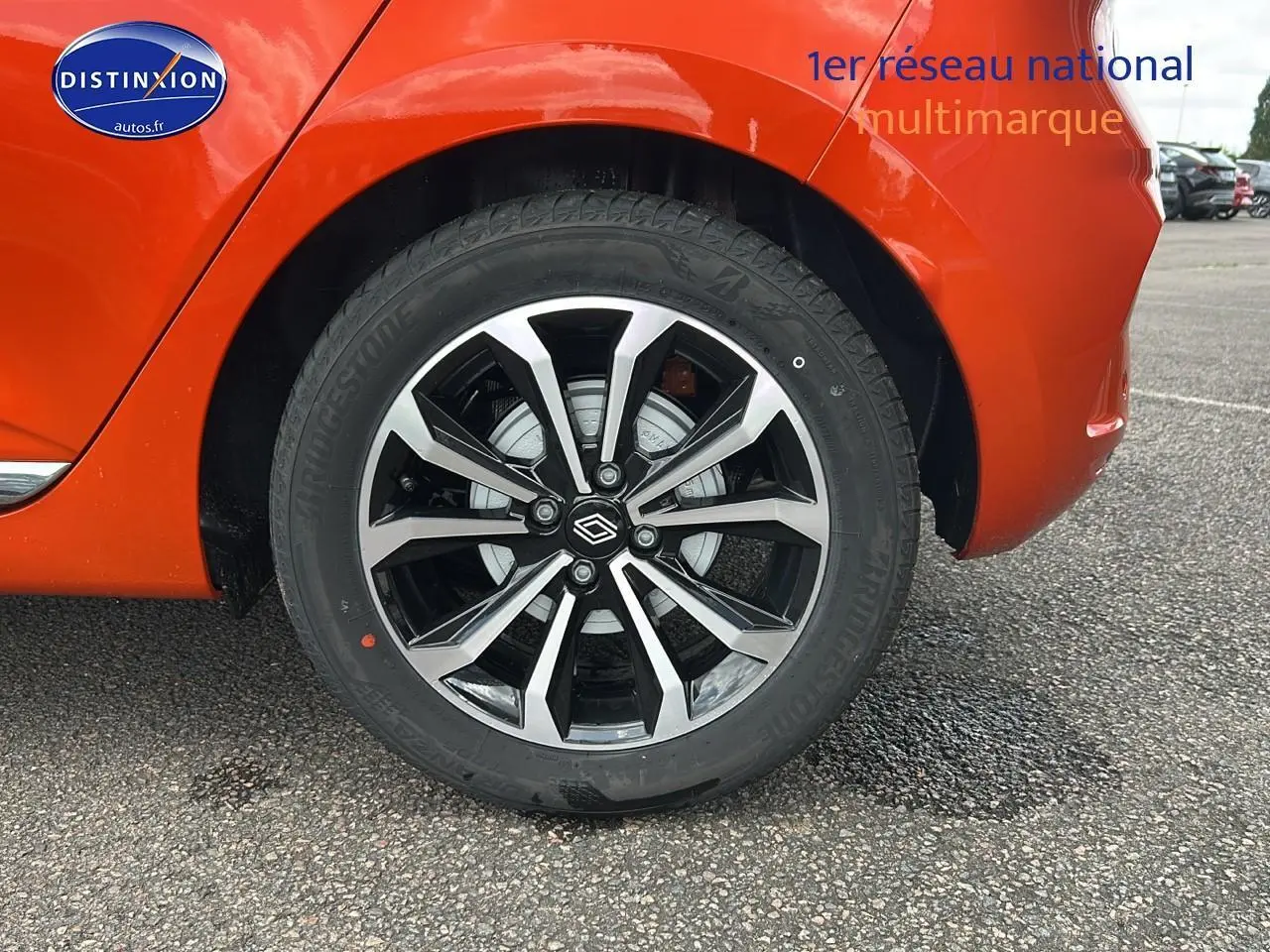 Gros plan sur la roue arrière droite de la Renault Clio V orange Valencia, mettant en valeur la jante alu au design moderne.