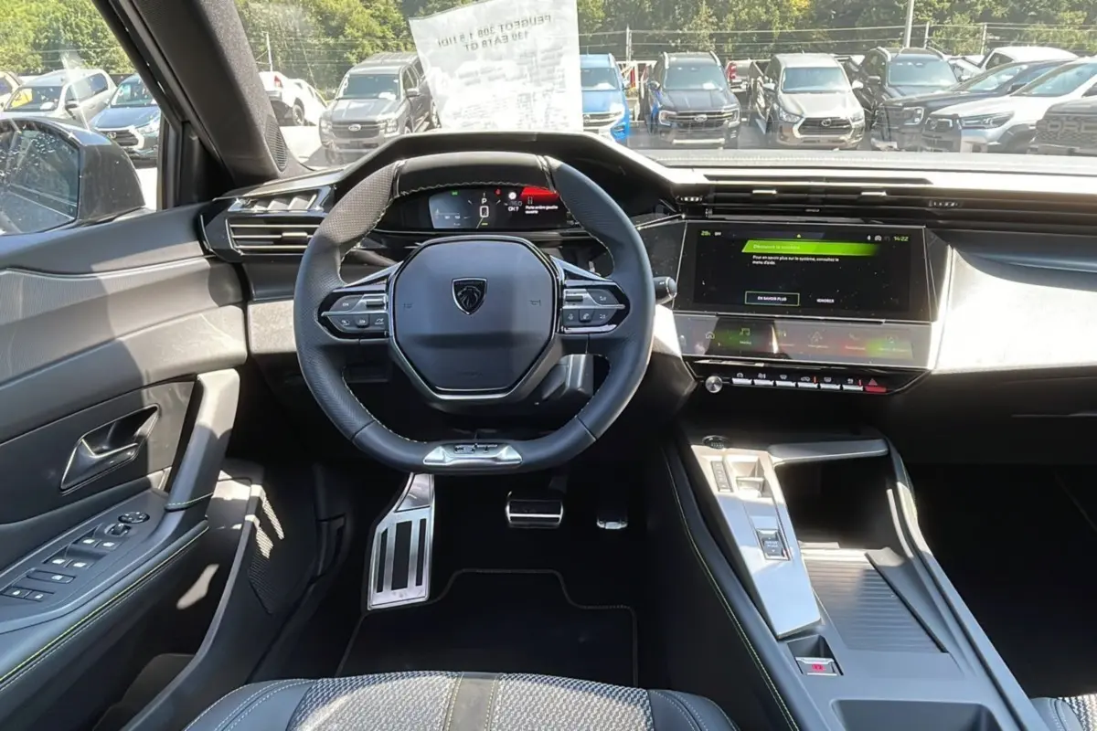 Intérieur moderne de la Peugeot 308 2025, vue du poste de conduite avec volant compact et écran tactile central.