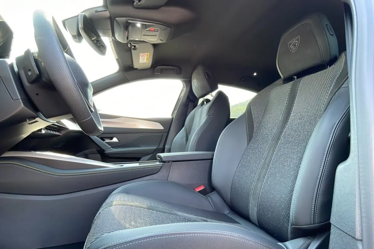 Intérieur de la Peugeot 308 2025, vue côté gauche sur les sièges avant en cuir noir avec logo GT brodé sur les appuie-têtes