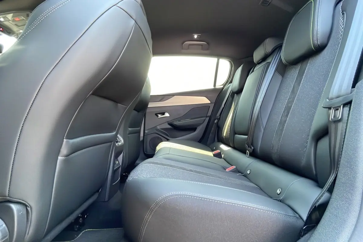 Vue latérale droite de l'intérieur arrière de la Peugeot 308 2025 gris selenium, sièges en cuir noir avec surpiqûres blanches.