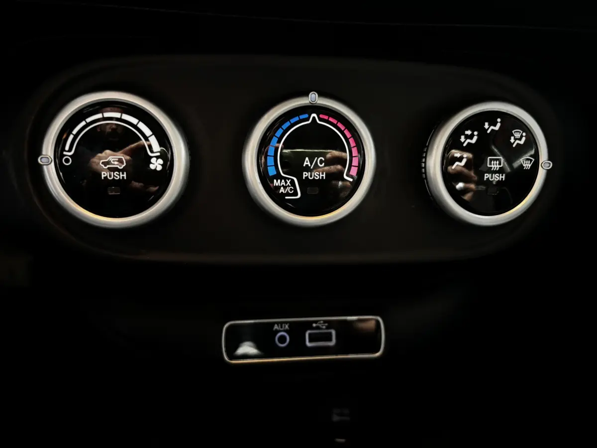 Gros plan sur les commandes de climatisation et connectiques USB/AUX du tableau de bord noir de la Fiat 500X.