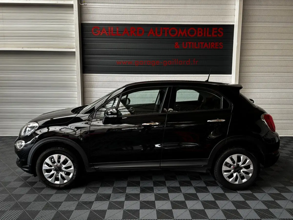 Vue latérale droite d'une FIAT 500X noire de 2018, compacte et élégante, avec jantes argentées et poignées chromées.