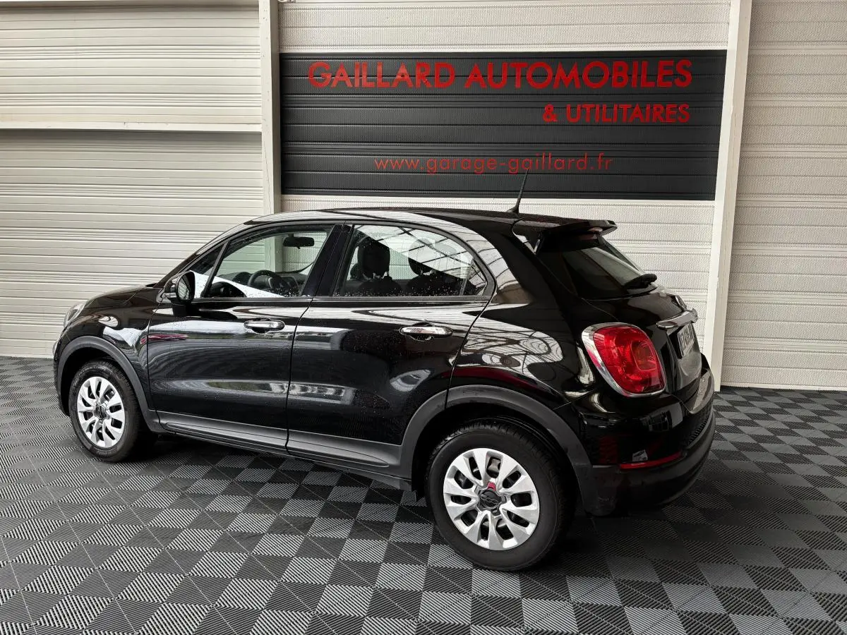 Vue 3/4 arrière droite d'une FIAT 500X noire 2018, avec jantes argentées et détails chromés sur les poignées.
