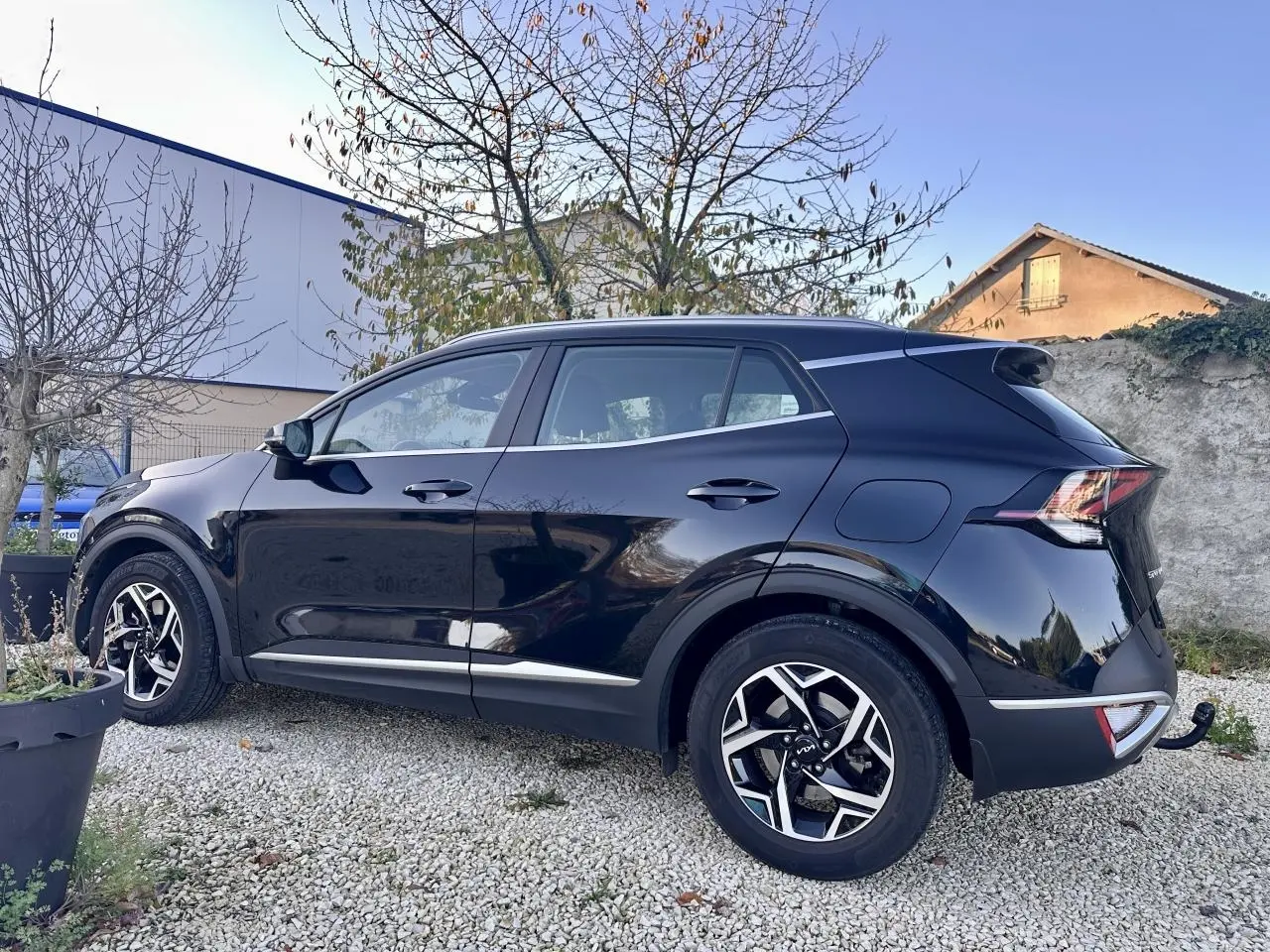 KIA SPORTAGE noir vu de profil côté gauche, avec jantes alliage et attelage de remorque visible à l'arrière.