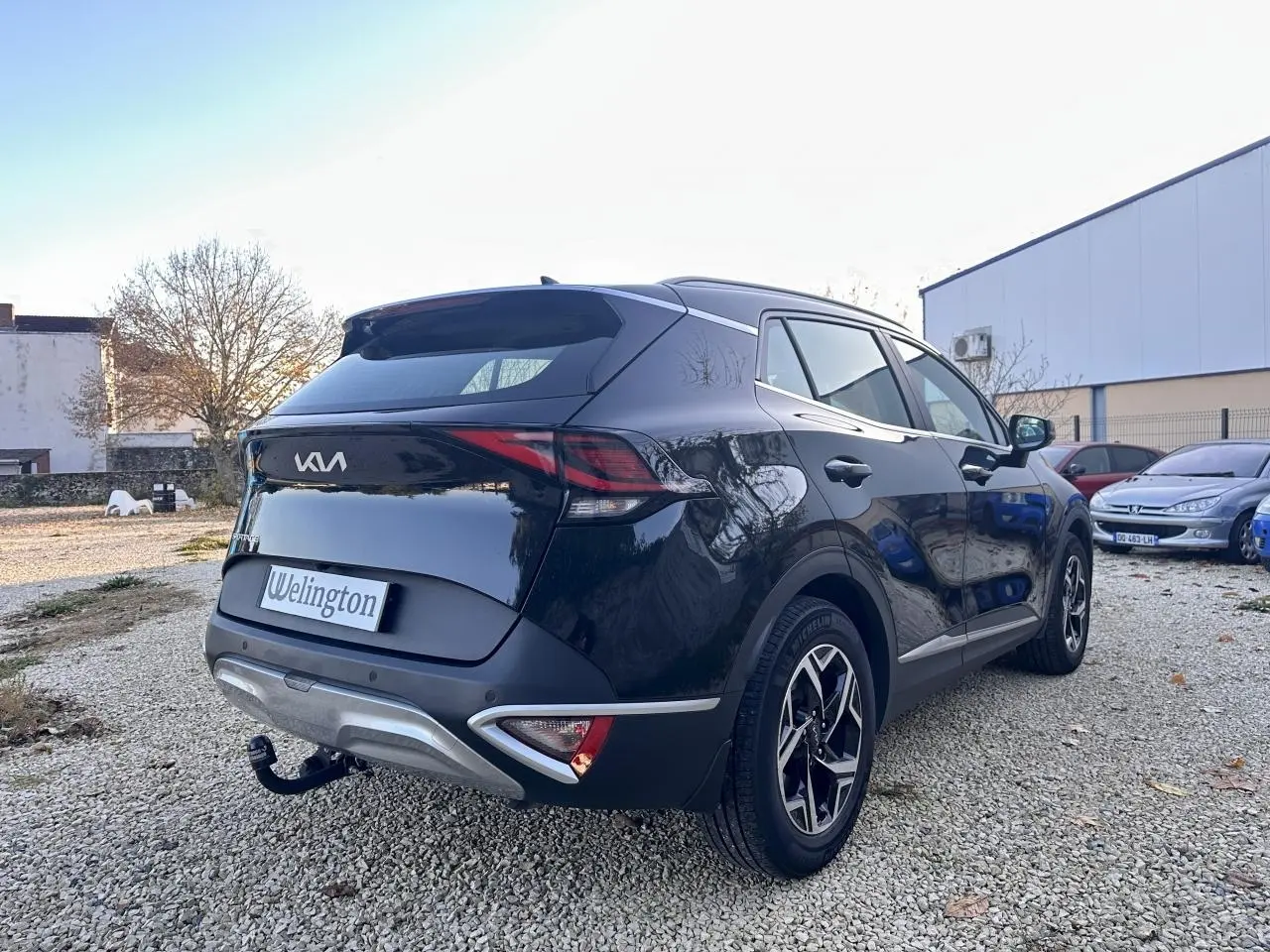 Vue 3/4 arrière droite du Kia Sportage noir 2023 avec feux arrière LED et attelage de remorque visible.