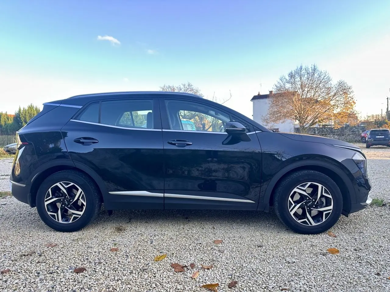 Profil côté gauche du Kia Sportage noir 2023 avec jantes alliage et détails chromés sur les bas de caisse.