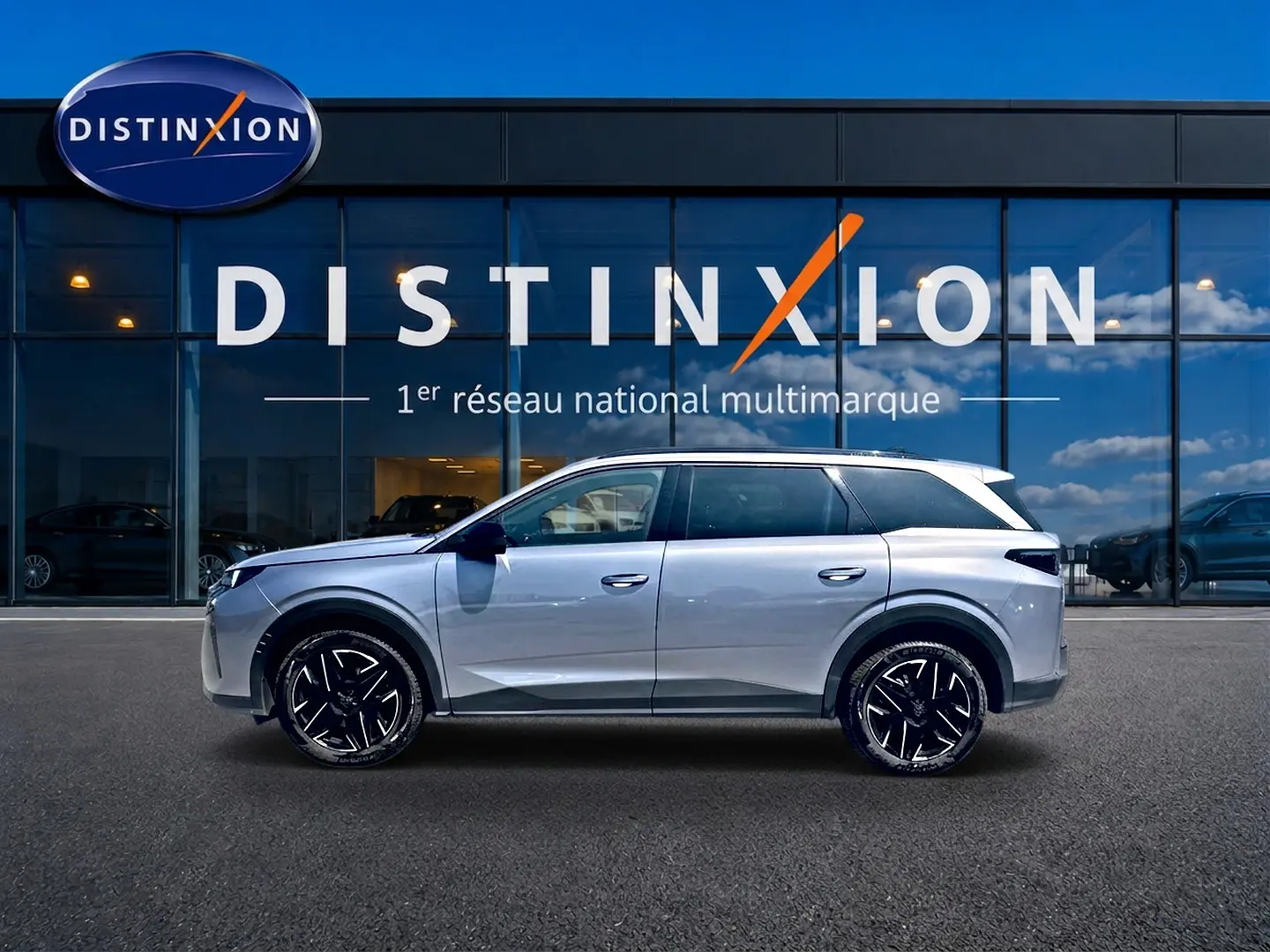 Peugeot 5008 Hybrid 145 allure gris artense vue de profil droit devant une vitrine Distinxion, jantes alu noires.