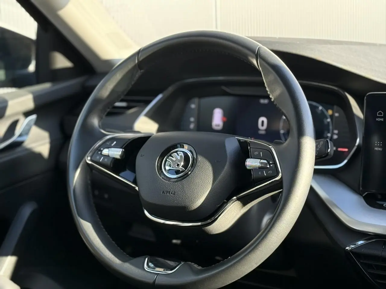 Volant cuir noir de Skoda Octavia Combi 2022 avec commandes intégrées et tableau de bord numérique en arrière-plan.