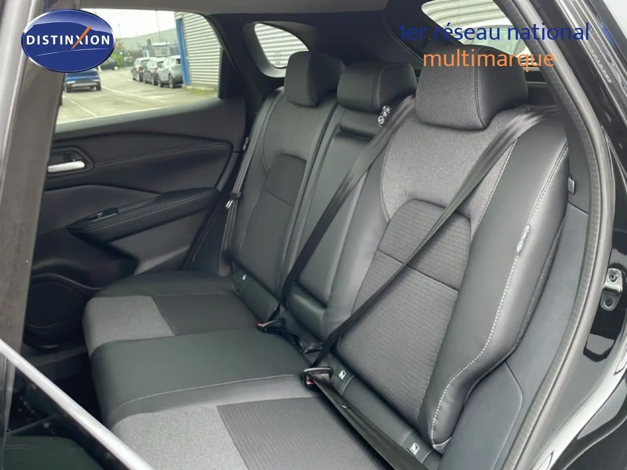 Vue intérieure arrière du Nissan Qashqai 1.5 E-POWER 2025, sièges bi-matière cuir et tissu gris foncé.