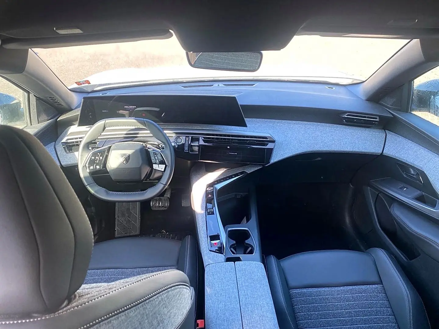 Vue intérieure avant du Peugeot 5008 Hybrid 145 allure e-dcs6 2025, avec tableau de bord gris clair et volant cuir noir.