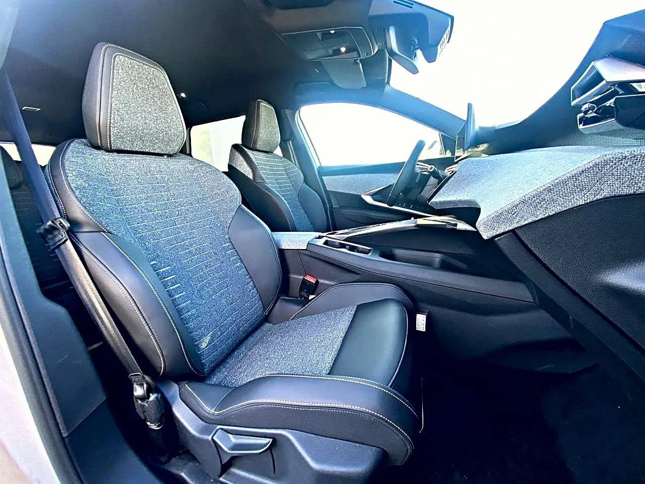 Vue intérieure côté passager avant du Peugeot 5008 Hybrid 145 allure e-dcs6 2025 avec sièges tissu bleu et cuir noir.